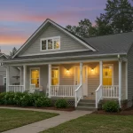 A charming senior-friendly cottage with a front porch, surrounded by landscaped greenery and a peaceful neighborhood setting. The image conveys comfort, independence, and a sense of community.