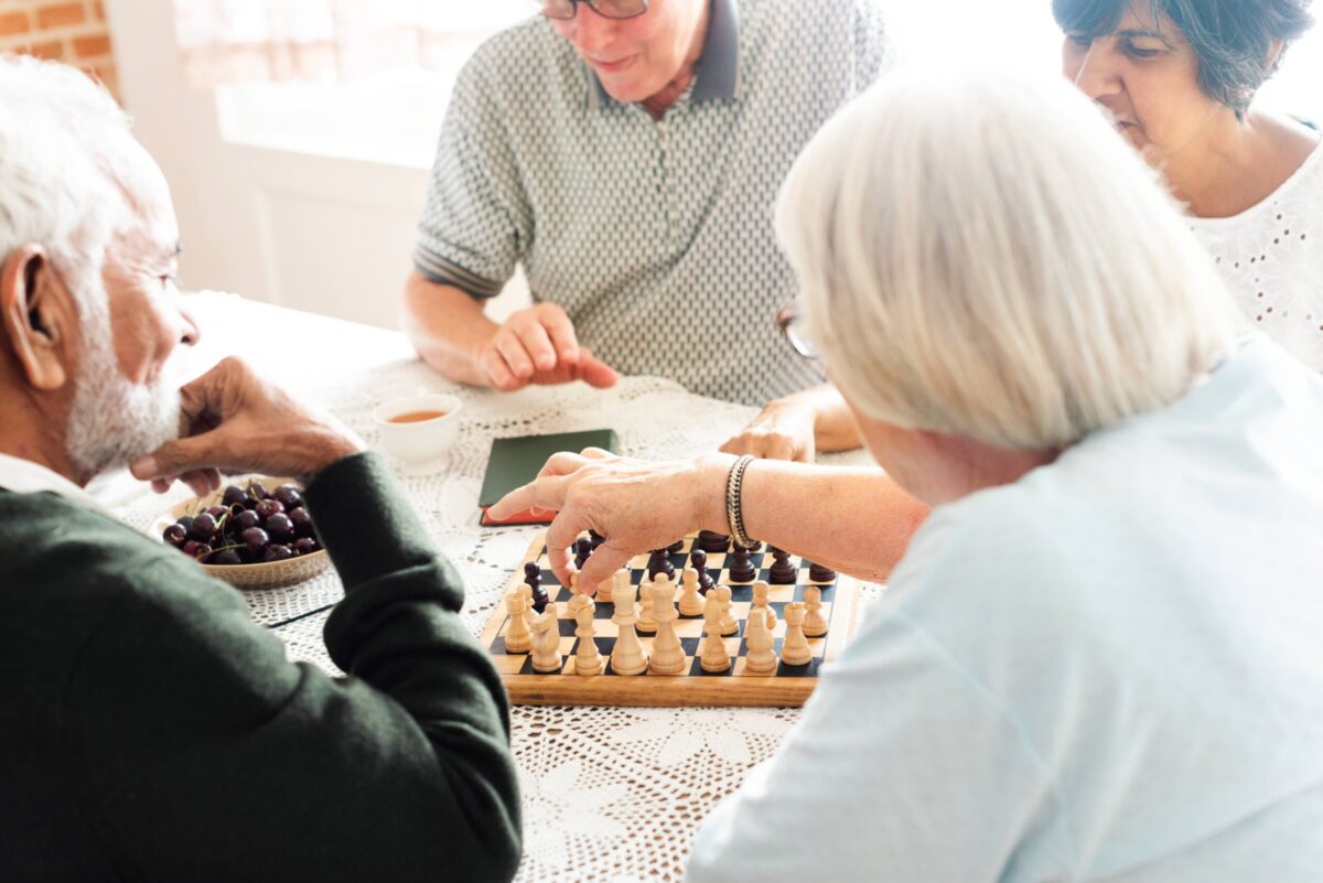 Older adults enjoy chess and conversation—social engagement for seniors in action.
