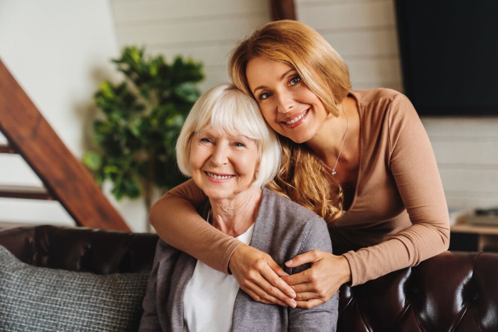 Smiling older adult and supportive family member sitting together, representing the difference between independent vs. assisted living.