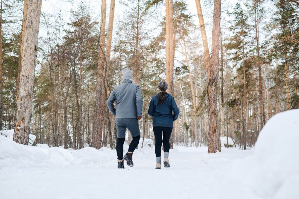 Older adults enjoying winter activities for seniors in Blue Ridge by walking together along a snowy forest path