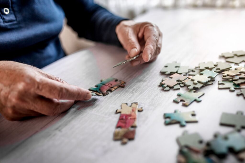 Close-up of older adult’s hands working on a jigsaw puzzle, challenging common myths about senior living.