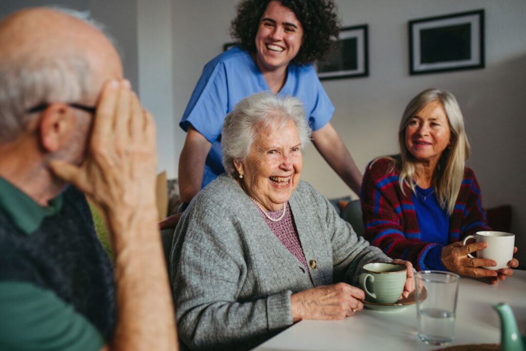 Older adults and a caregiver sharing a joyful moment, emphasizing the importance of social interaction to address senior isolation risks